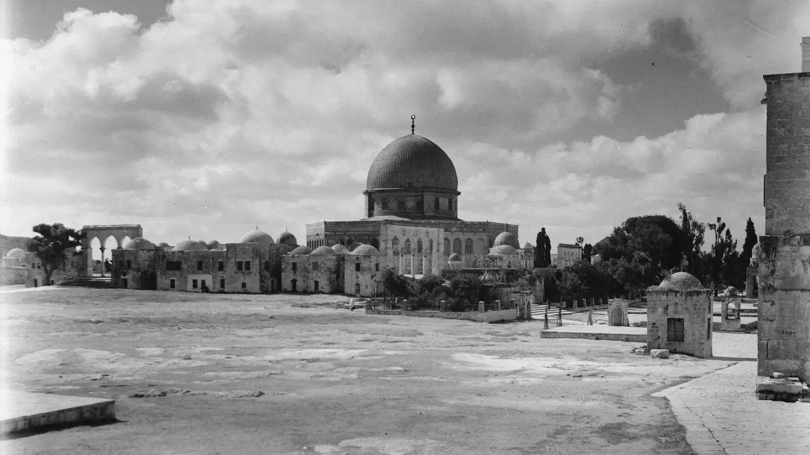 The Dome of the Rock across the wide stone courtyard of the sanctuary in Jerusalem, under a cloudy sky