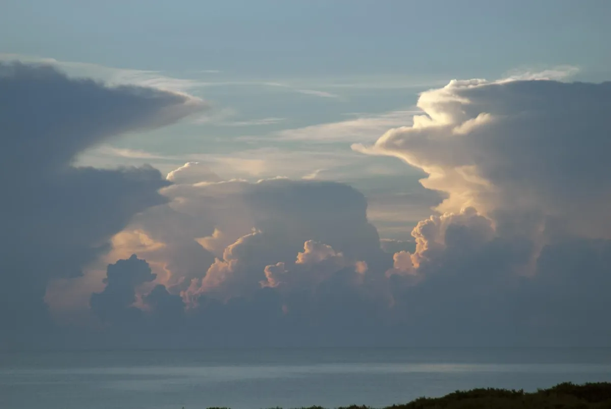 Hoch aufragende Gewitterwolken, wie Berge über dem Meer in der Morgendämmerung aufgetürmt